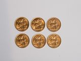 a close up of a bunch of gold coins sitting on top of a white surface