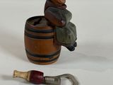 a figurine of a man sitting on a barrel with a bottle opener