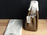 coach handbag in tan leather with a white tag and a white bag