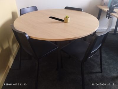 une table ronde avec quatre chaises et un vase posé dessus