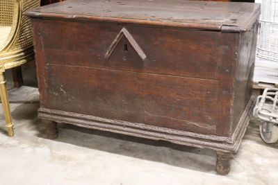 an old wooden chest sitting in a room next to a wicker chair