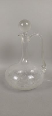 une bouteille en verre transparent avec une anse, posée sur une table