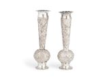 une paire de vases en argent empilés l'un sur l'autre sur une surface blanche
