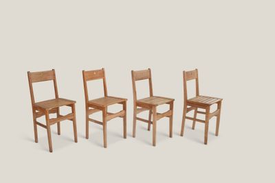trois chaises en bois assises l'une à côté de l'autre sur une surface blanche