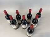 six bottles of red wine are lined up on a white surface