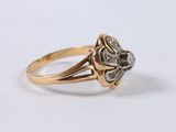 a close up of a gold and diamond ring on a white surface