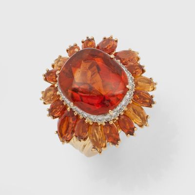 a close up of a ring with an orange stone surrounded by orange and white stones