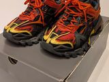 pair of black and orange running shoes in a box on a white surface