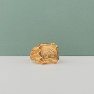 une photo d'une bague en or posée sur une table blanche