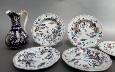 plusieurs assiettes et un pichet posés sur une table, avec un vase en arrière-plan