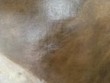 a close up of a brown leather chair with a gold frame