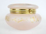 a pink glass jar with a gold lid on a white surface