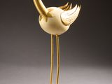 a gold statue of a bird with a long neck and legs