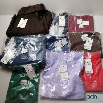 de nombreux t-shirts de différentes couleurs posés sur une table blanche