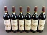 six bottles of wine lined up in a row on a table