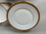 several white and gold plates with gold rims on a table