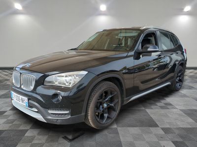 La BMW X1 est garée dans un garage dont le sol est recouvert d'un motif à damier.
