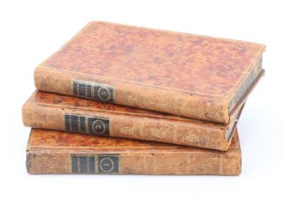 trois vieux livres empilés sur une surface blanche