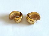 une paire de boucles d'oreilles dorées posées sur une surface blanche, sur fond blanc