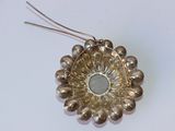 une broche en forme de fleur argentée posée sur une surface blanche