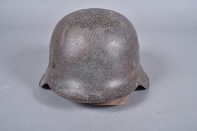 Un vieux casque repose sur une surface blanche, sur fond gris.
