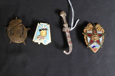 trois insignes et une épée sont posés sur une surface noire