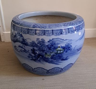 un grand vase bleu et blanc posé par terre
