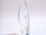 un vase en verre transparent à la base incurvée, posé sur une surface blanche