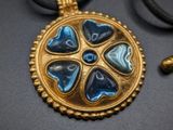 a gold and blue pendant with hearts on it