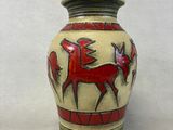 un vase orné d'un motif représentant un cheval sur fond blanc