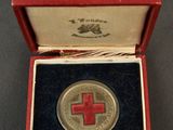 a red cross medal in a red box on a black surface