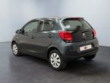 the back of a small grey car is parked in a room