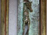 une statue en bronze représentant un homme tenant un cheval, dans un cadre
