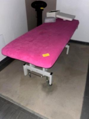 un lit rose dans une chambre où se trouve une chaise noire