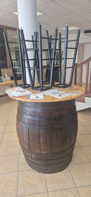 a large wooden barrel with a bunch of chairs in it
