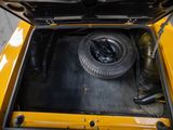a yellow car with a tire in the trunk of it
