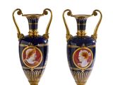 une paire de vases bleus et dorés posés sur une surface blanche