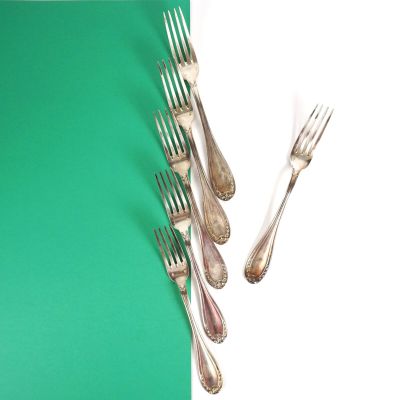 cinq fourchettes et un couteau sur une table verte et blanche