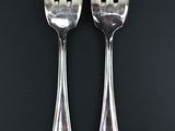 pair of silver plated fork and spoons on a black background