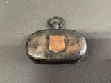 an old silver case with a brown emblem on it