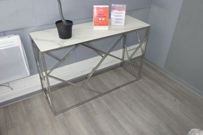 une petite table sur laquelle se trouve une plante, près d'une fenêtre