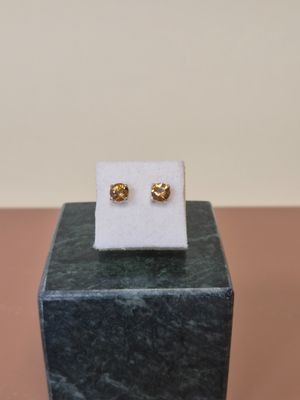 une paire de boucles d'oreilles en or posées sur un bloc de marbre, sur une table