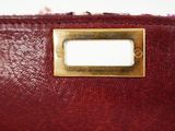 the inside of a red purse with a gold plate on it