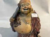 une statue représentant un Bouddha souriant tenant un téléphone portable