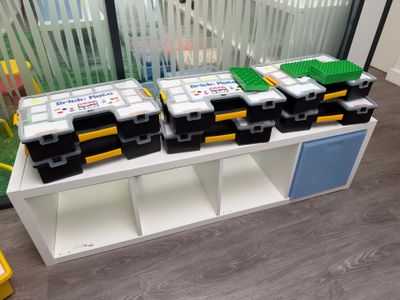 de nombreuses boîtes de Lego posées sur une étagère dans une pièce