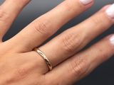 La main de la femme tient une bague en or sertie d'un diamant.