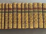 un lot de douze livres aux couvertures dorées posé sur une table