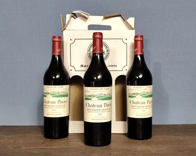 three bottles of red wine sit in front of a cardboard box