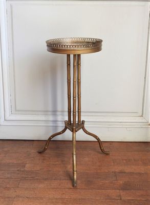 une table d'appoint ancienne en laiton avec un plateau en verre, posée sur un parquet