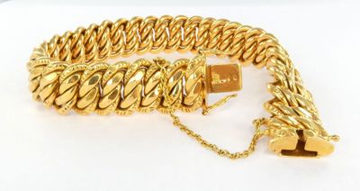 gros plan d'un bracelet en chaîne en or sur une surface blanche